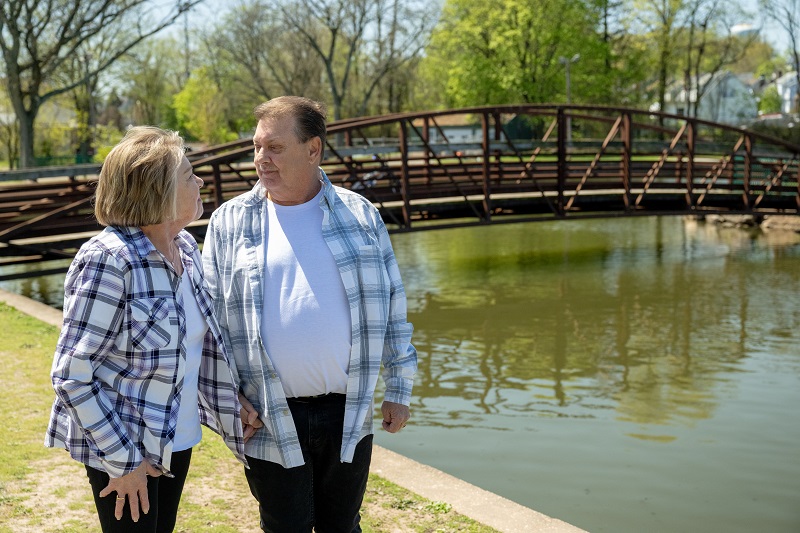 Frances Clark and her husband walking outside, looking at each other and smiling.