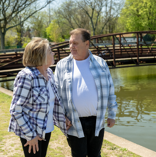 Frances Clark and her husband walking outside, looking at each other and smiling.