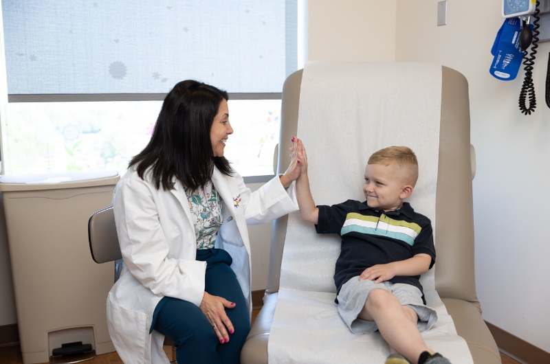 Smiling six-year-old boy who beat cancer gives his doctor a high five.