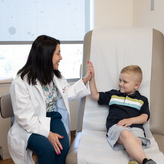 Smiling six-year-old boy who beat cancer gives his doctor a high five.