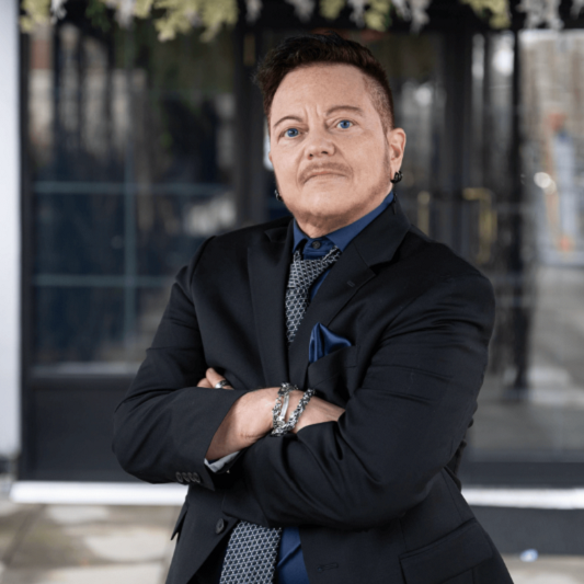 Micky Petrillo, 60, looks at the camera with his arms folded in front of him.