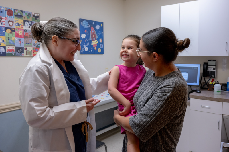 3-year old Audrina Sorbera smiles at her doctor as her mother holds her.