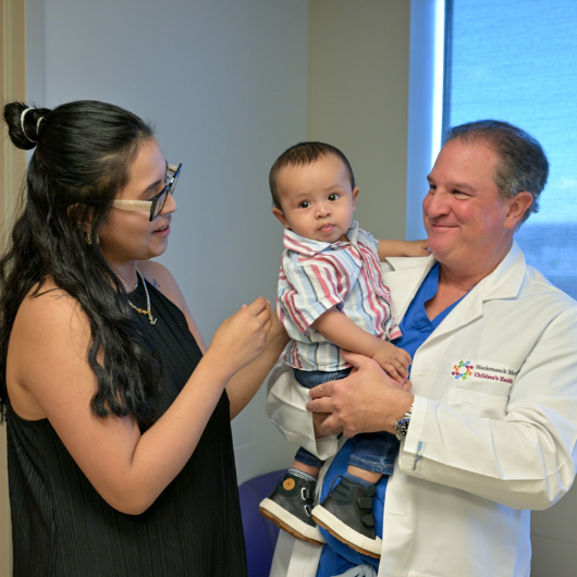 A brown-haired baby boy named Ethan Barnuevo Mija, his mother and his doctor enjoy a happy moment together.
