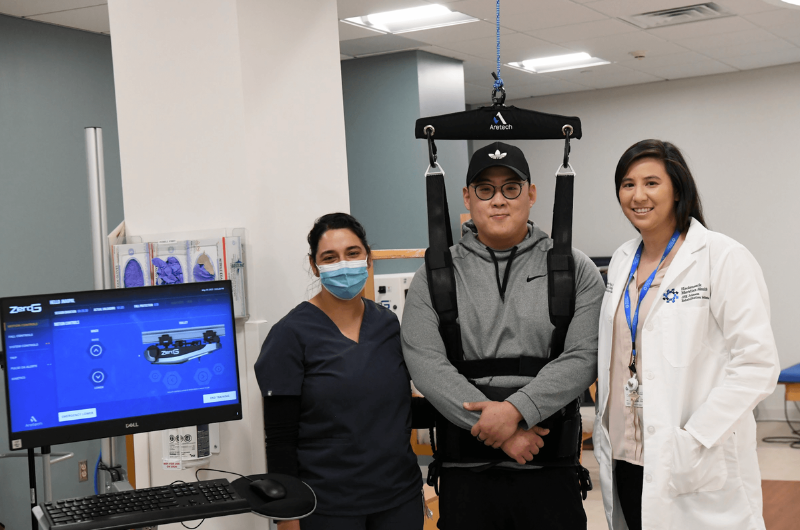 32-year-old David Suh stands with his rehabilitation team while wearing a Zero-G harness.   