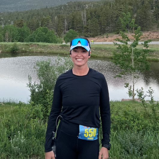 Brunette woman Jennifer Lucero smiles at the camera after running a half marathon.