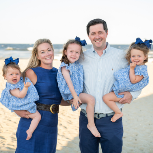 Allison Adams stands on a beach with her husband and three young daughters.