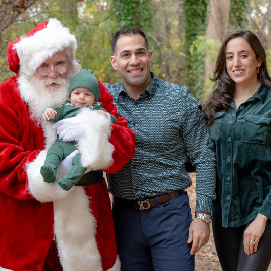 Ron Fierro stands next to his wife and Santa Claus, who is holding a baby.