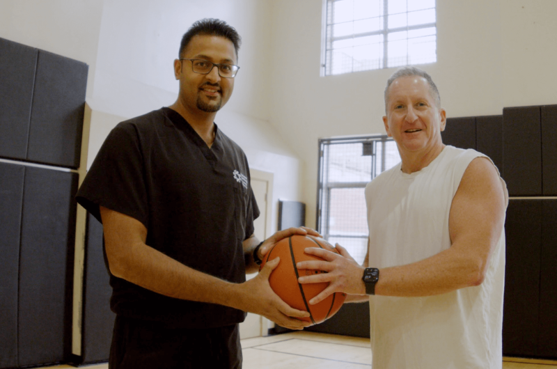 63-year-old Robert Cohan holds a basketball next to orthopedic surgeon Siddhant Mehta, M.D., Ph.D.