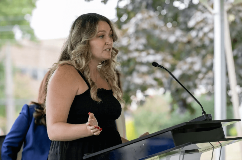 Michelle Colucci stands at a podium and speaks.