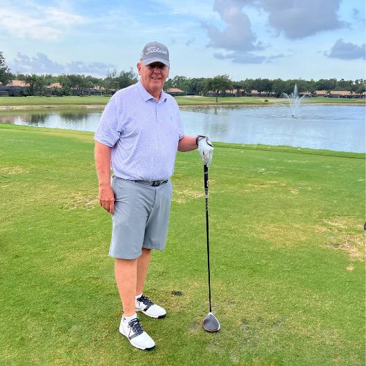 Standing on a golf course, 69-year-old Jim Schleifer holds his golf club.