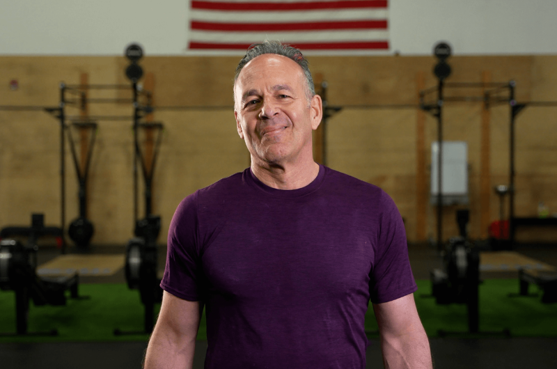 A close-up of patient Ed Gaelick standing in front of gym equipment.