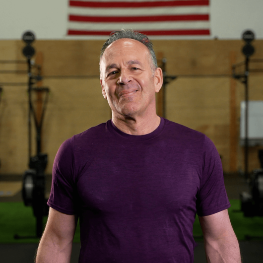 A close-up of patient Ed Gaelick standing in front of gym equipment.
