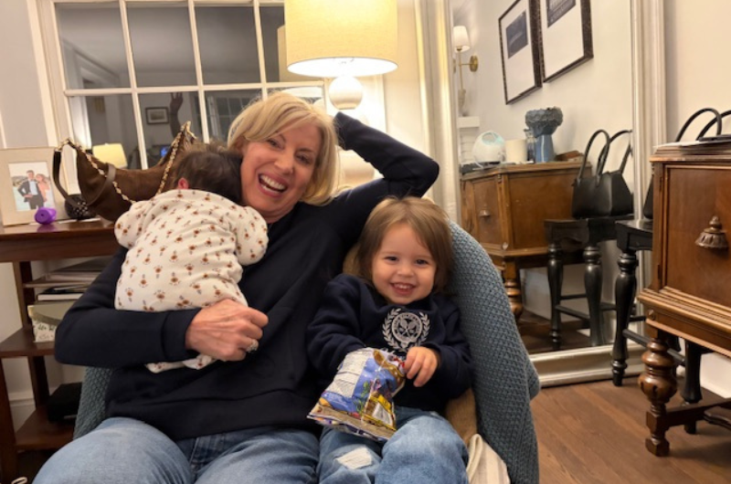 Patricia Ashmore sits in a chair with her two grandchildren.