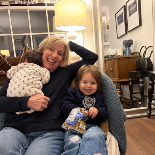 Patricia Ashmore sits in a chair with her two grandchildren.