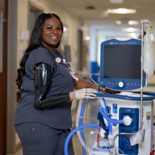 Ciera Coleman shows her prosthetic arm in a hospital hallway.