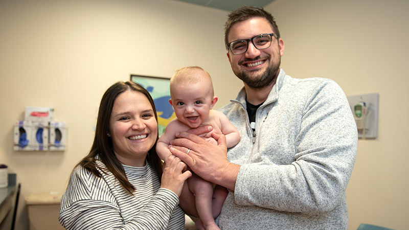 Shown with his parents, baby Ryan Moser smiles at the camera.