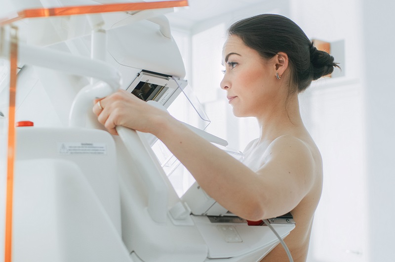 Side view of a woman in her 40's getting a mammogram for early breast cancer detection.