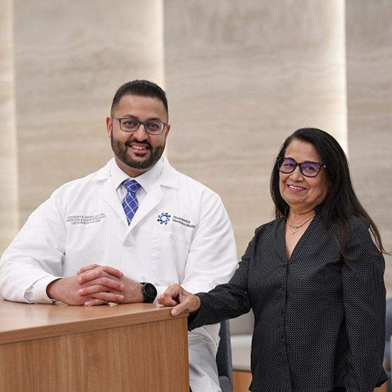 Two orthopedic surgeons standing together in a hospital setting, smiling at the camera.