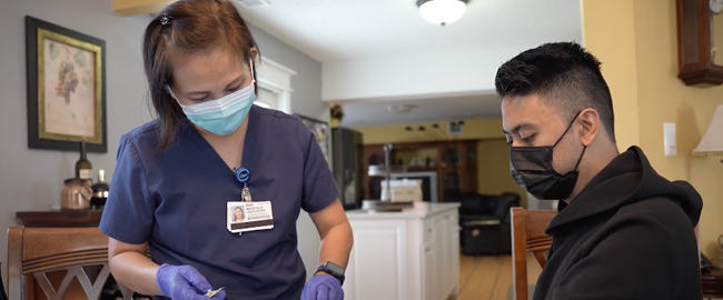 Nurse wearing mask attending to a man sitting down