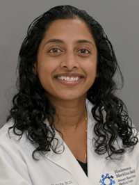 Women with curly brown hair wearing a white lab coat