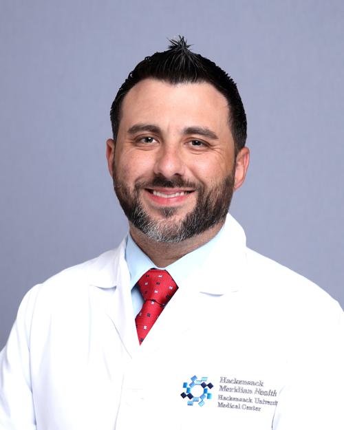 man wearing white coat with short black hair and a short beard