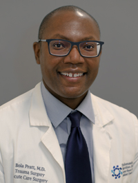 Man with short black hair smiling wearing glasses and a white lab coat