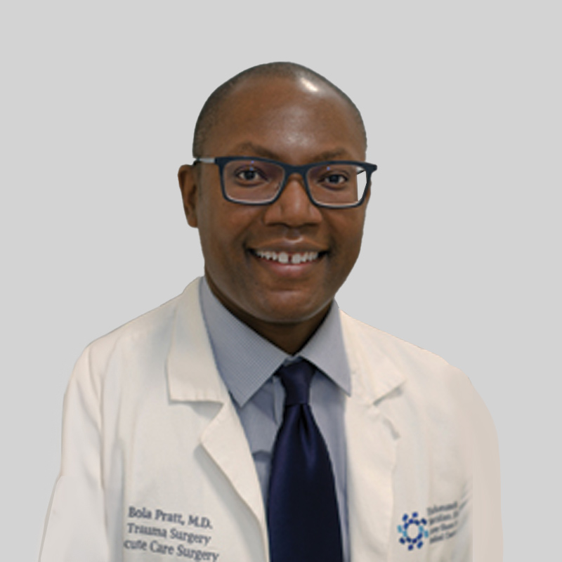 Man with short black hair smiling wearing glasses and a white lab coat