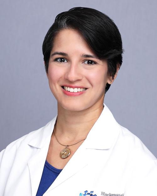 Women with short black hair wearing a white jacket with blue under shirt