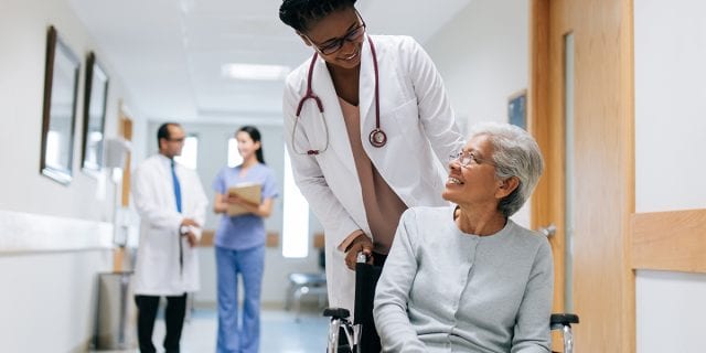 provider pushing an elderly woman in a wheelchair