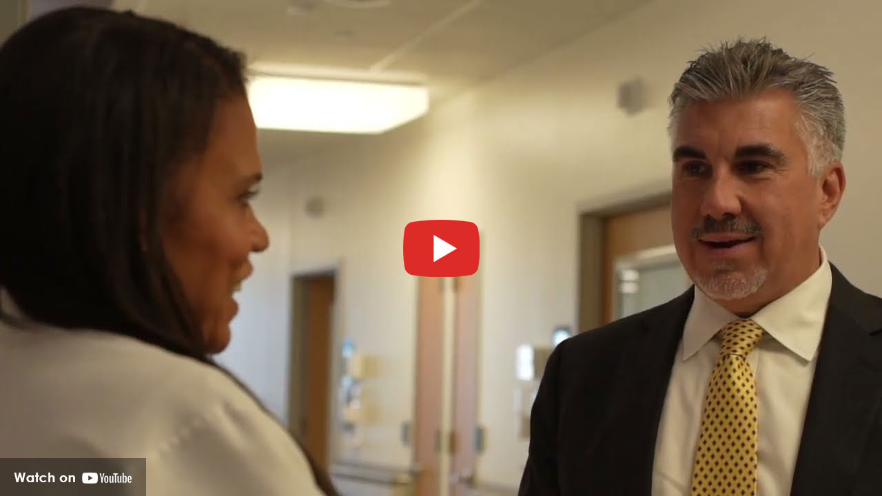 Healthcare professional speaking with a man in a hallway setting