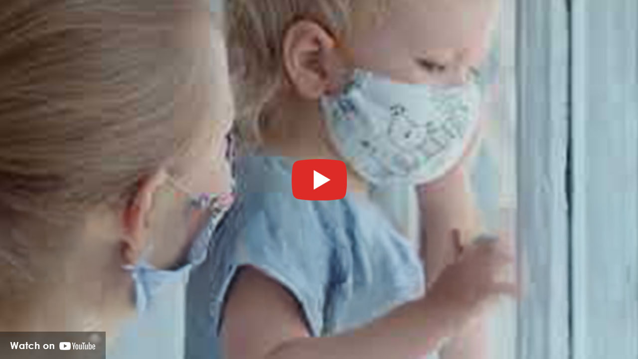 Child wearing face mask looking out window during COVID isolation