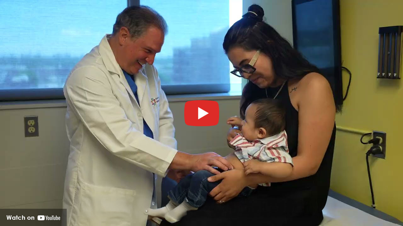 Doctor examining a baby while a parent holds the child in a medical exam room