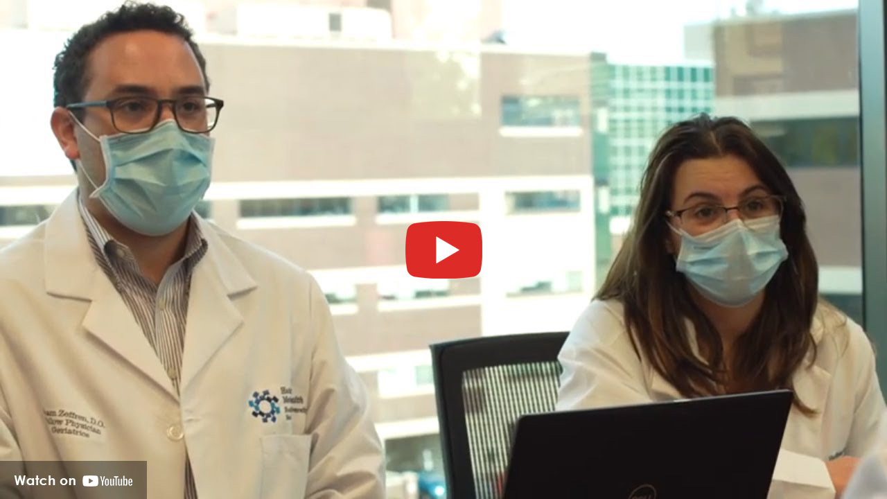 Two doctors wearing masks seated at a table during a meeting