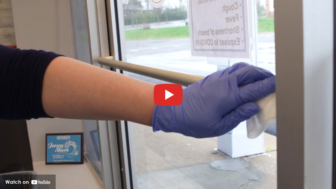 A purple gloved hand washing a window.