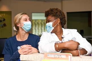 Two masked nurses smiling thru masks