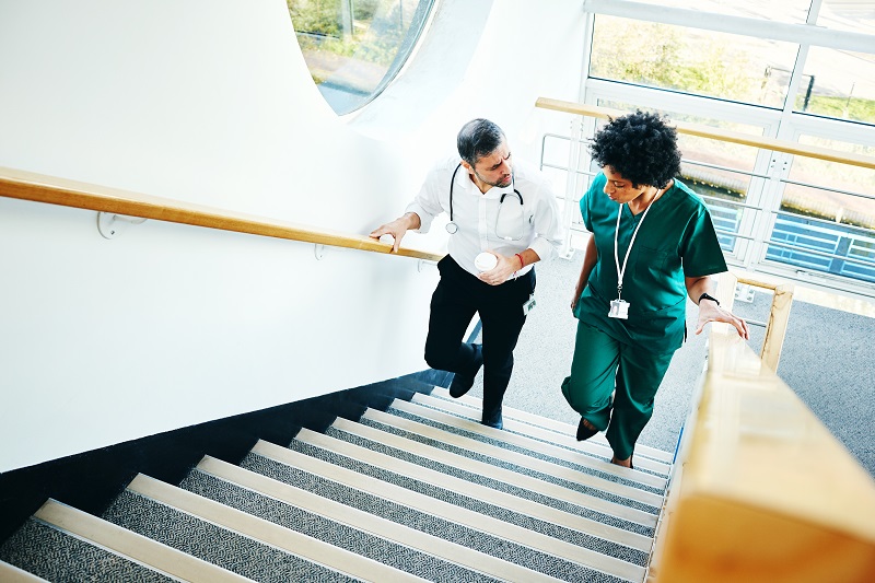 Two doctors walking on a staircase, having a conversation, in between cases in the hospital