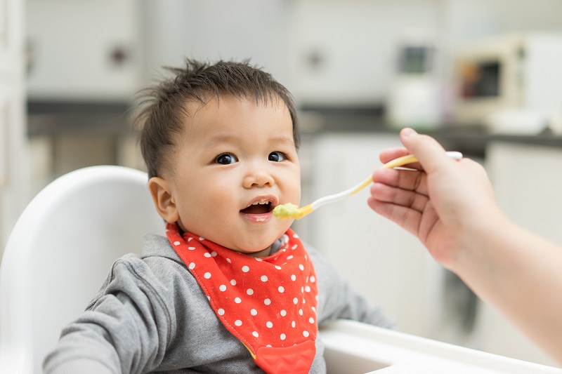 Asian baby being spoon fed some baby food