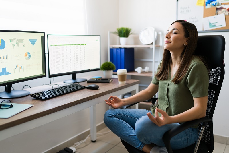 Young woman working from home taking a break during the work day to meditate and relax.