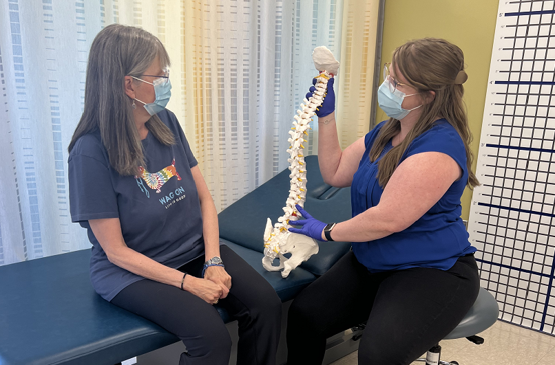Monessa Van Cise and her rehabilitation therapist showing her a spine replica to discuss scoliosis 