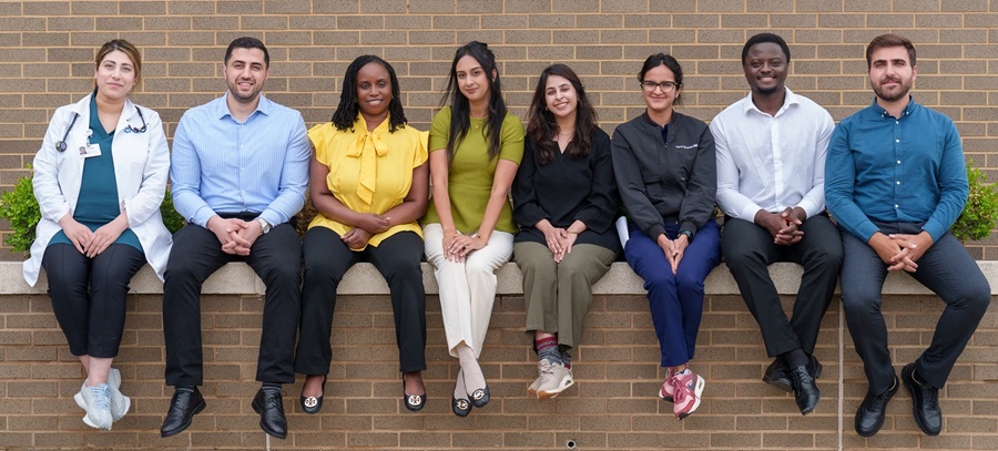 JFK Internal Medicine Residents sitting on a brick wall.