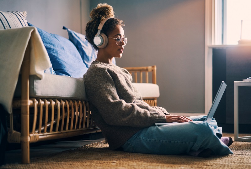 Young woman listening to loud music with headphones while on her laptop. 
