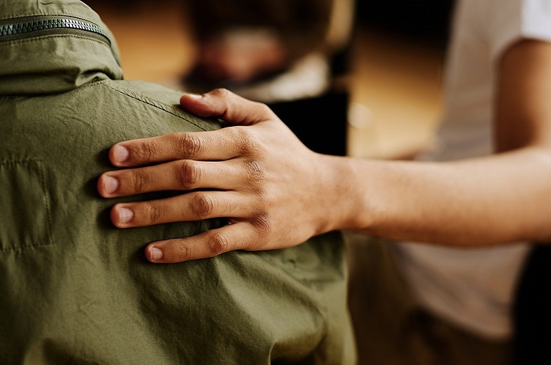 A hand on a person's back, a friend offering comfort; representative of support for mental health conditions and addiction