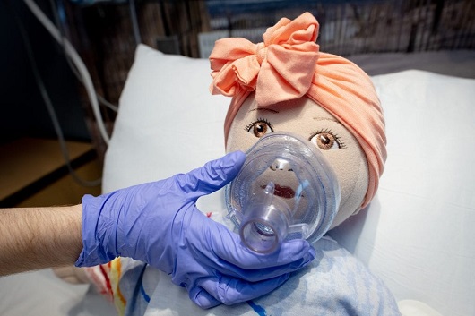 doll getting oxygen through a mask to show a patient how a face mask works