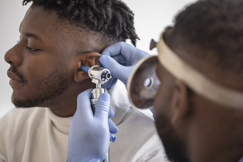 Close up of a male doctor carefully holding the ear of his patient to establish a clearer view of the inside of his ear, to see if he requires hearing aids