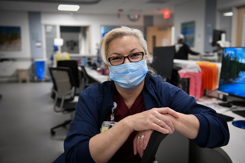 A nurse, behind a desk, smiling at an urgent care