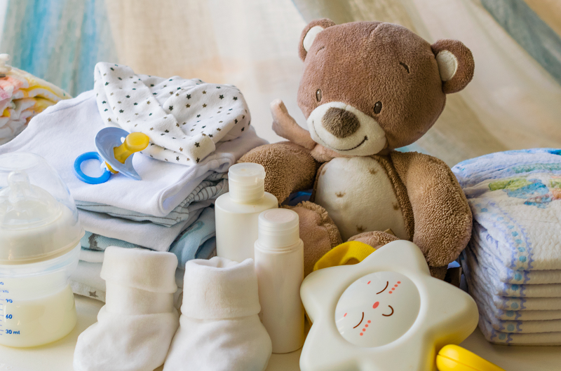 Newborn baby items including bottles, socks, teddy bear, burp clothes and diapers.