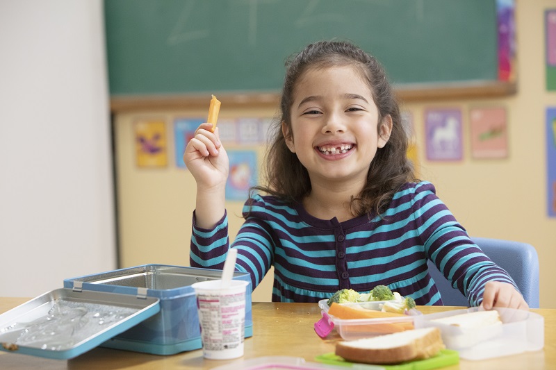 Young girl enjoying healthy snacks at school.
