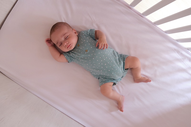Small baby sleeping peacefully and safely in their crib.