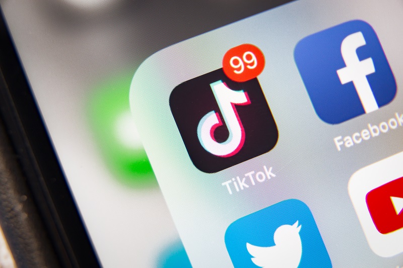 Close up view of a phone with the TikTok app and there are 99 notifications.