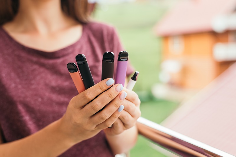 Young woman holding a bunch of e-cigarettes, vapes, or Jules. Toxic chemicals.